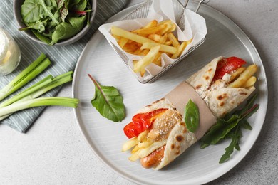 Delicious pita wrap with sausage, french fries and pepper on light gray table, flat lay