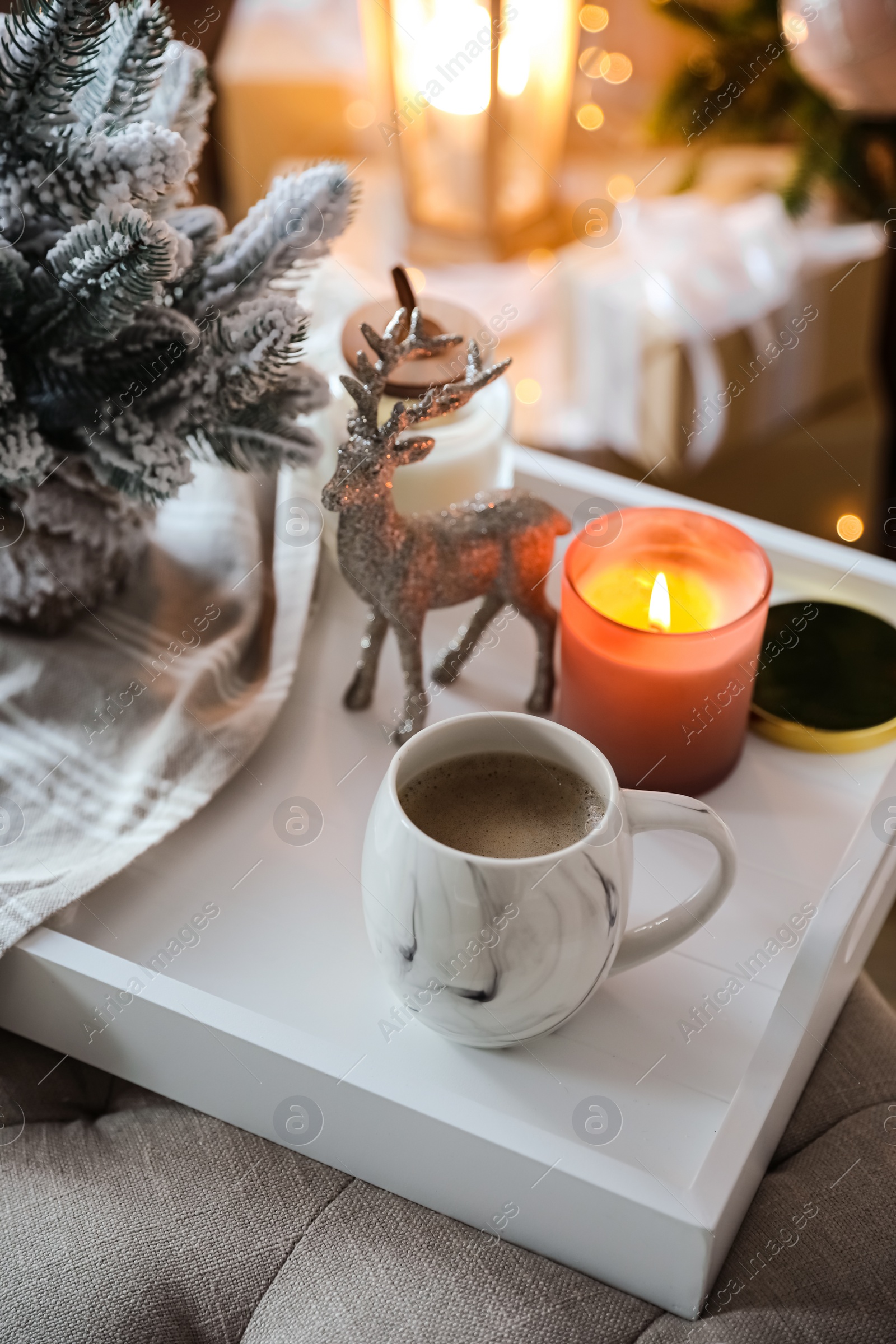 Photo of Cup of cocoa, candle and decorative deer on tray at home. Christmas celebration