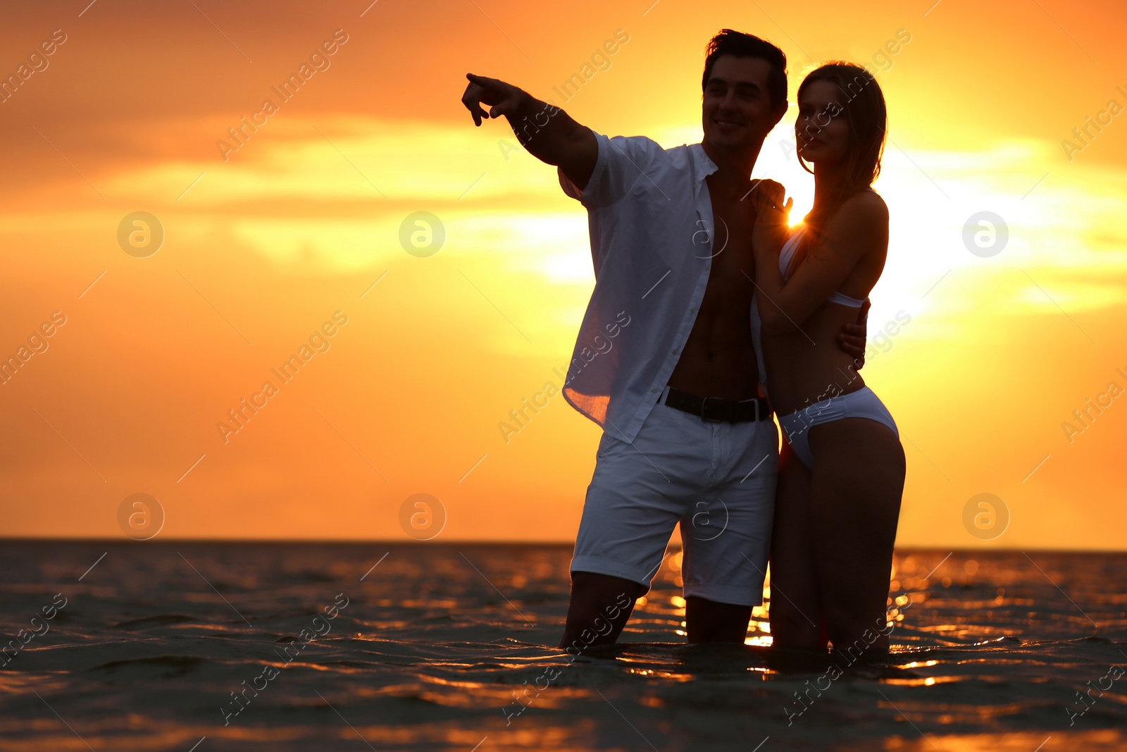 Photo of Happy young couple spending time together on sea beach at sunset