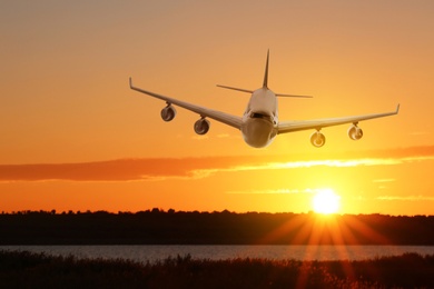 Image of Modern airplane landing at sunset. Air transportation