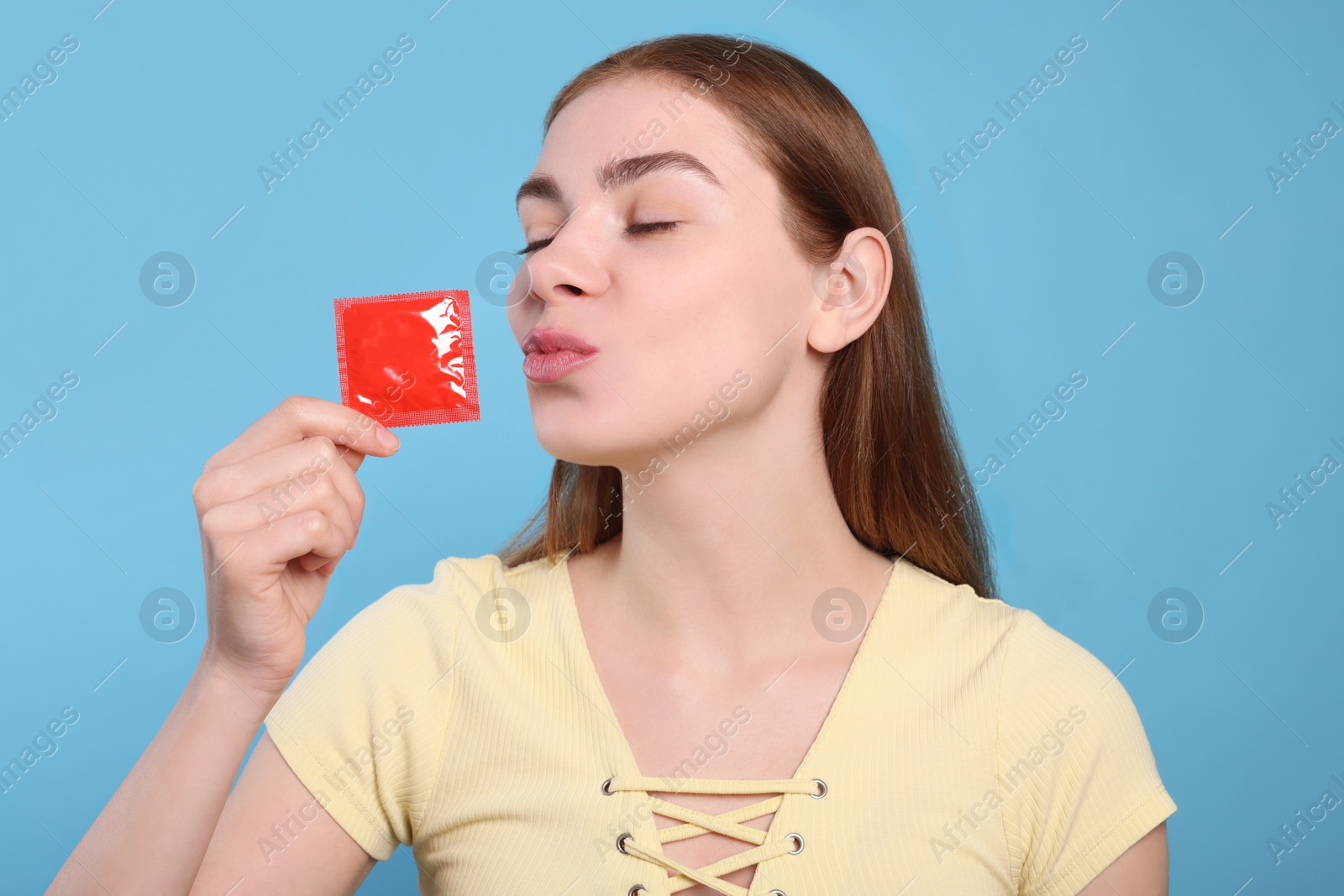Photo of Woman holding condom on turquoise background. Safe sex