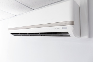 Modern air conditioner on white wall indoors, closeup view