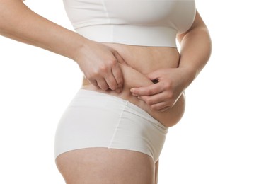 Woman touching belly fat on white background, closeup. Overweight problem