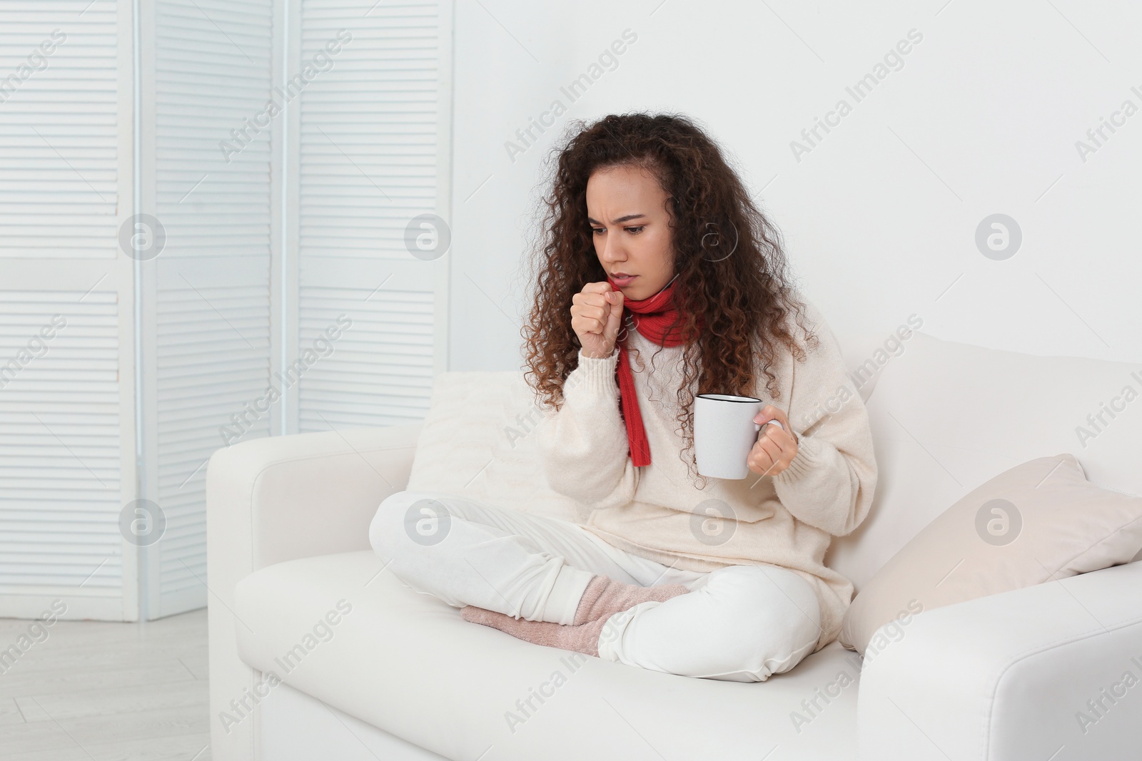 Photo of Sick African American woman with cup of hot drink at home