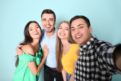 Photo of Young happy friends taking selfie against color background