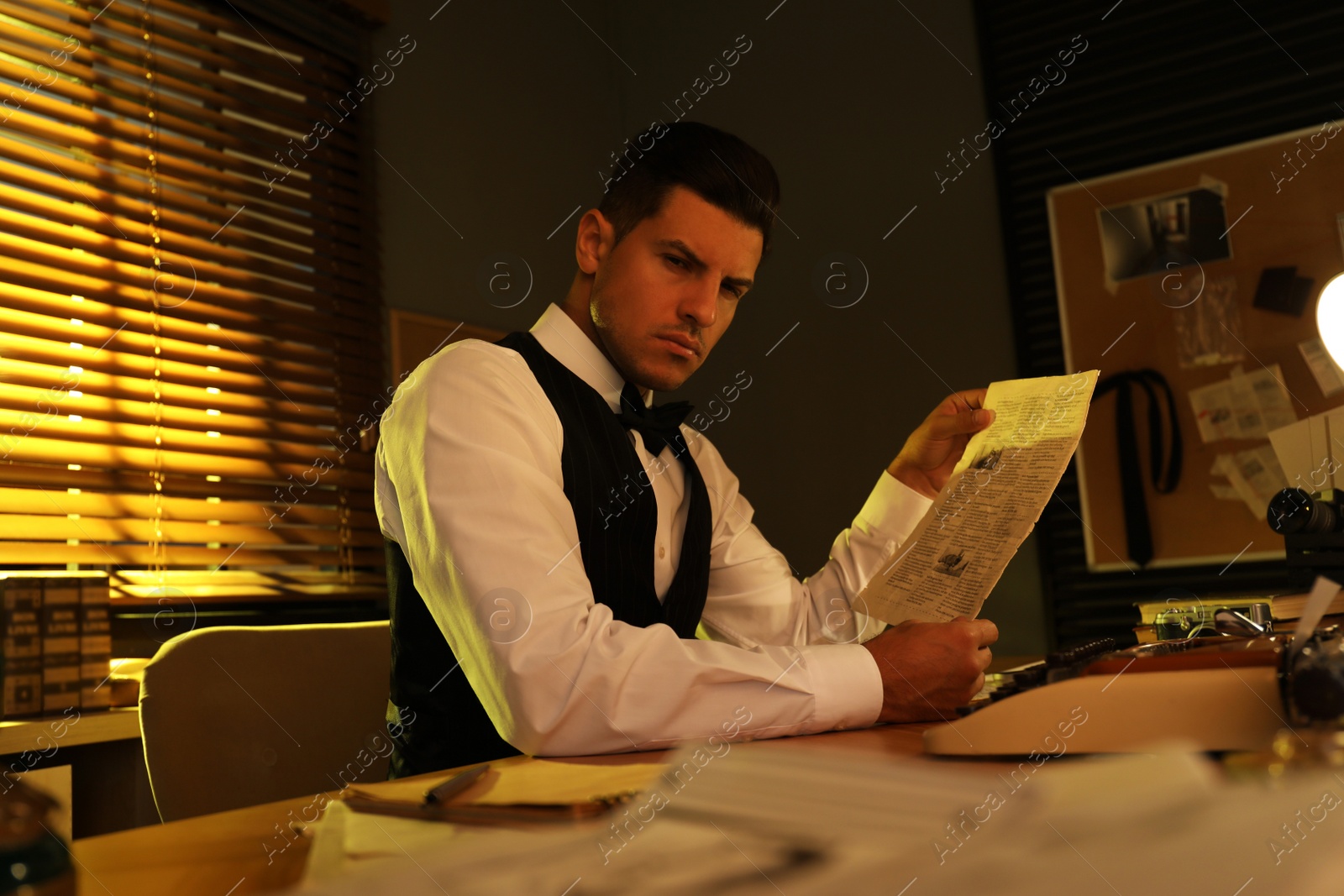Photo of Old fashioned detective reading newspaper at table in office