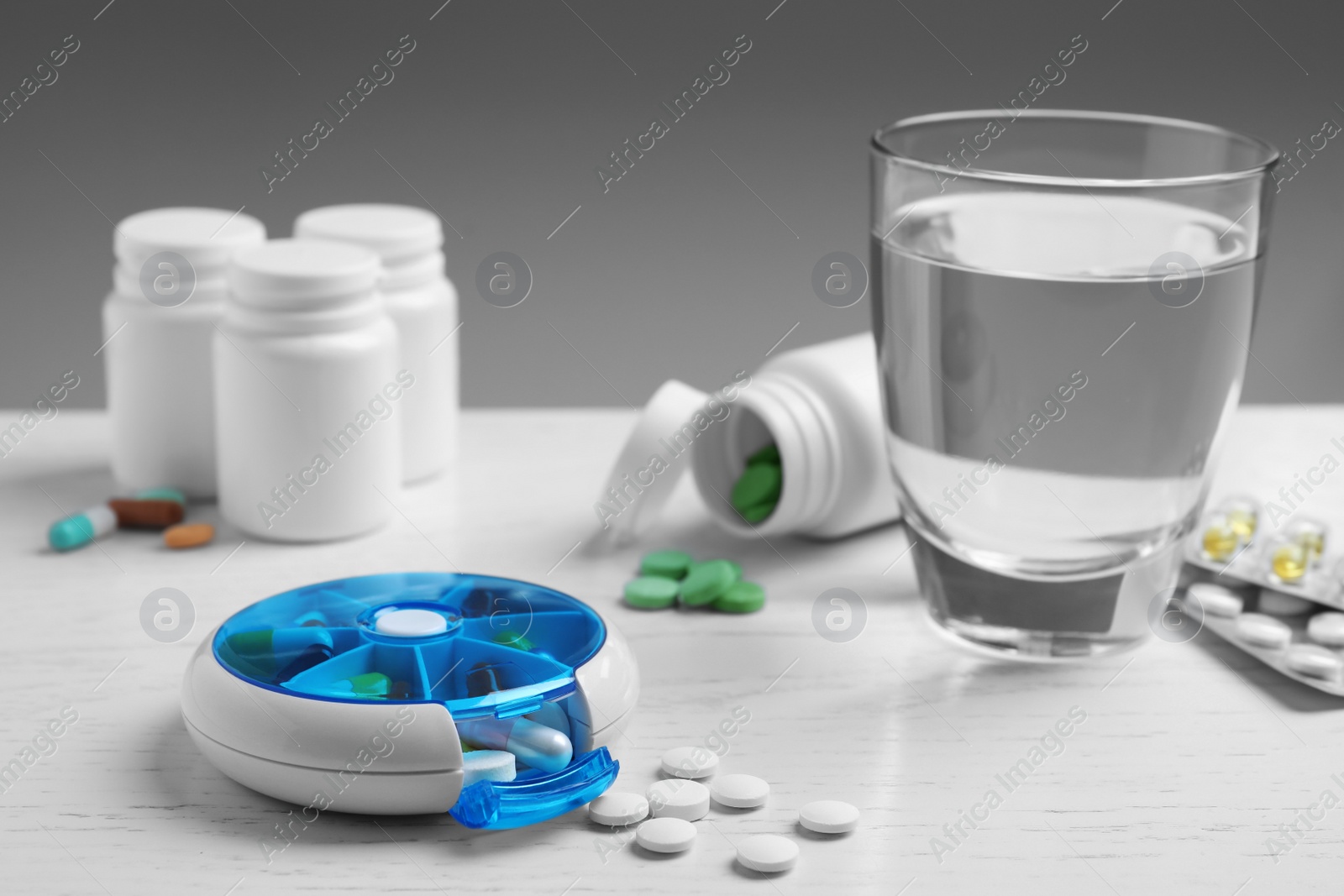 Photo of Pill box with medicaments on white wooden table