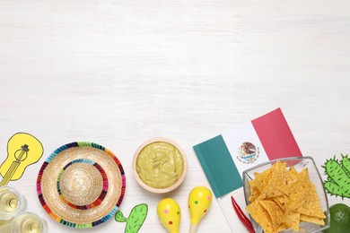 Photo of Mexican flag, maracas, tequila, nachos chips and sombrero hat on white wooden table, flat lay. Space for text