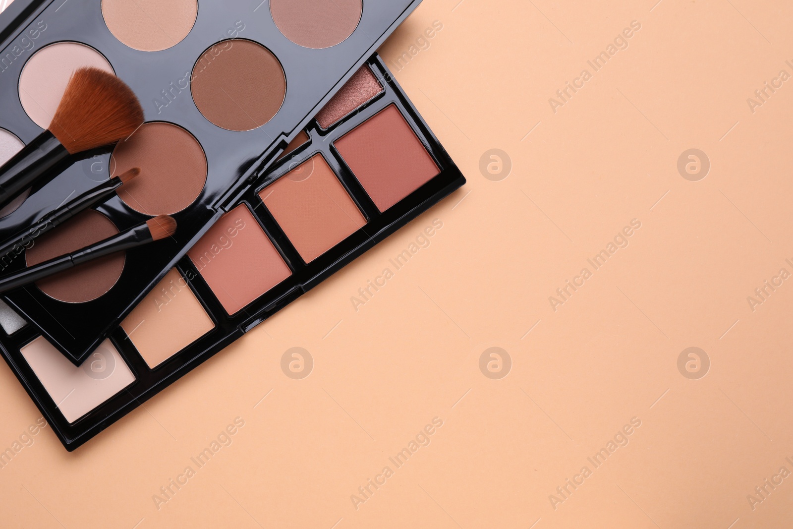 Photo of Colorful contouring palettes and brushes on beige background, flat lay with space for text. Professional cosmetic product