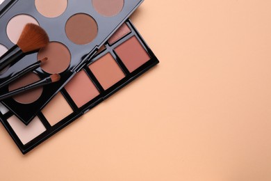 Photo of Colorful contouring palettes and brushes on beige background, flat lay with space for text. Professional cosmetic product
