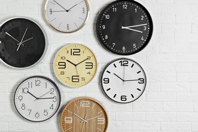 Photo of Different analog clocks hanging on white wall. Time of day