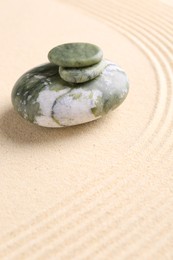 Photo of Zen garden stones on beige sand with pattern. Space for text