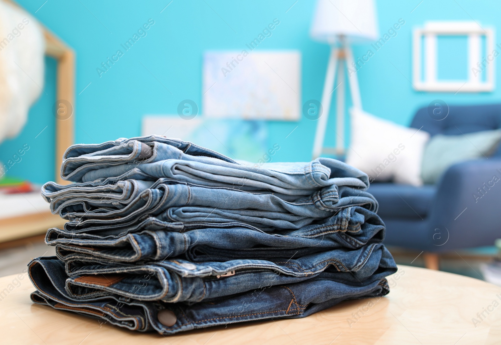 Photo of Stack of stylish jeans on table against blurred background