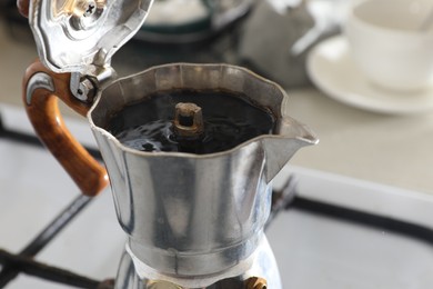 Photo of Brewing aromatic coffee in moka pot on stove indoors, closeup