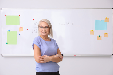 Mature teacher near whiteboard in modern classroom