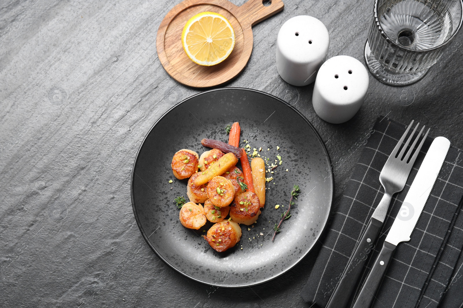 Photo of Delicious fried scallops served on dark gray textured table, flat lay. Space for text