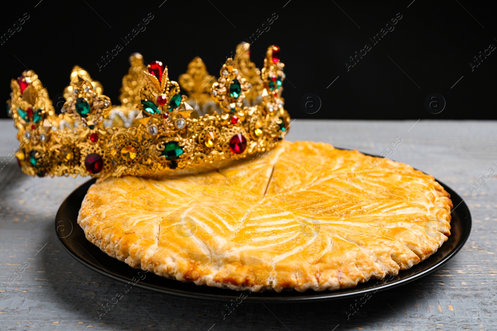 Photo of Traditional galette des rois with crown on grey wooden table, closeup