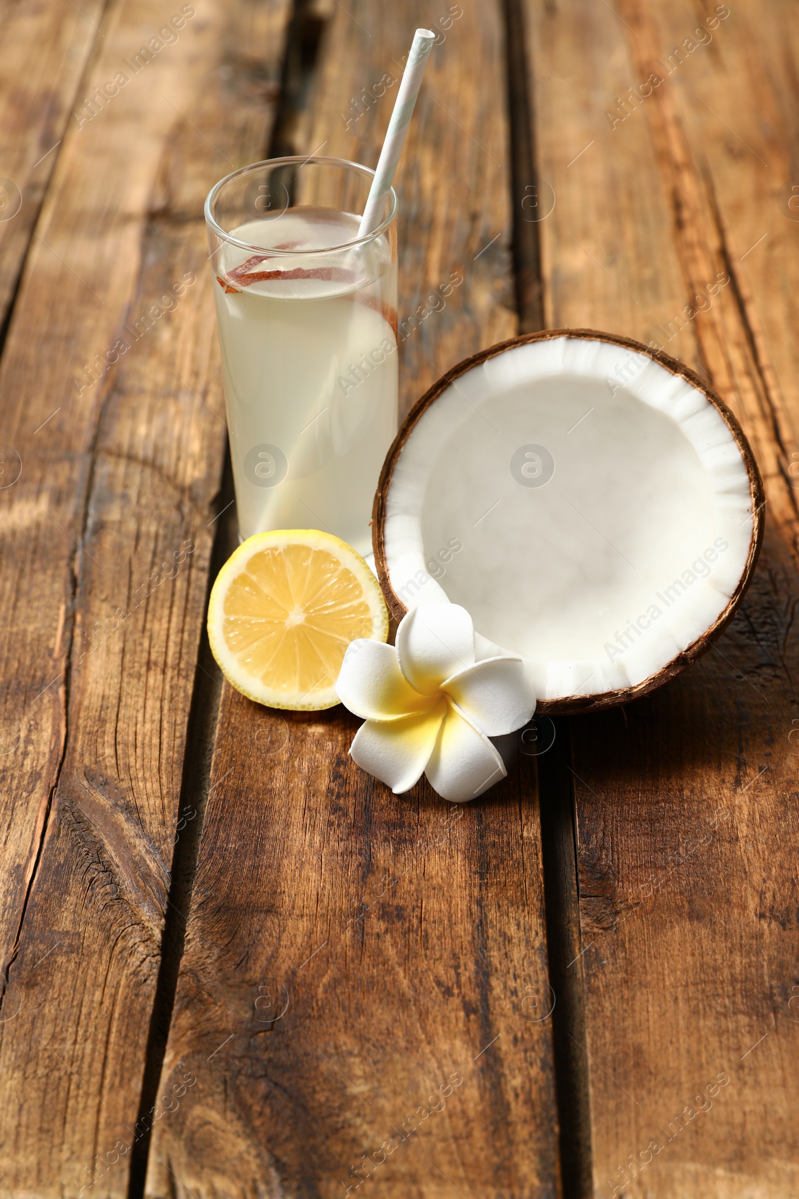 Photo of Composition with glass of coconut water and lemon on wooden table