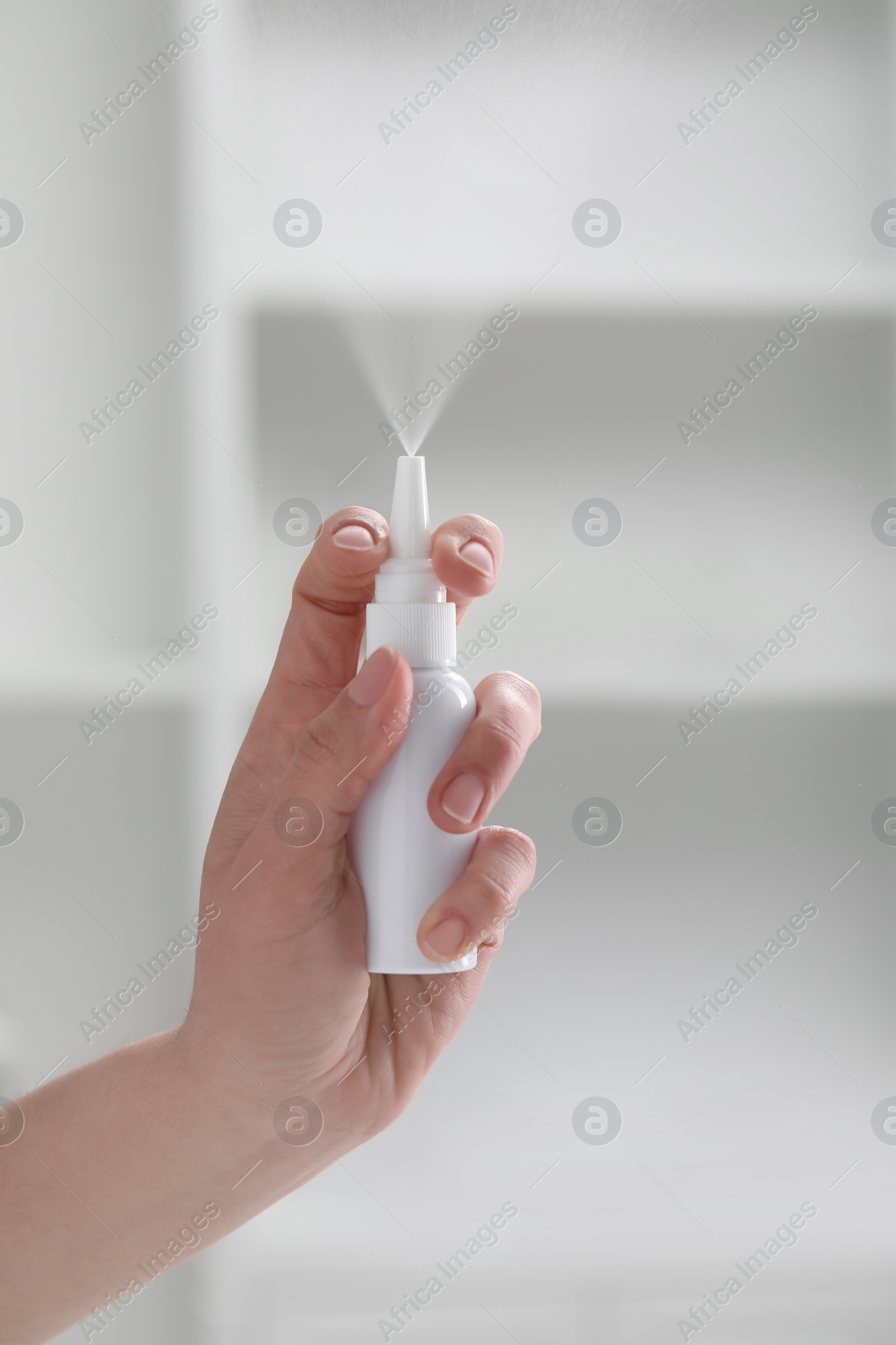 Photo of Woman using nasal spray indoors, closeup view