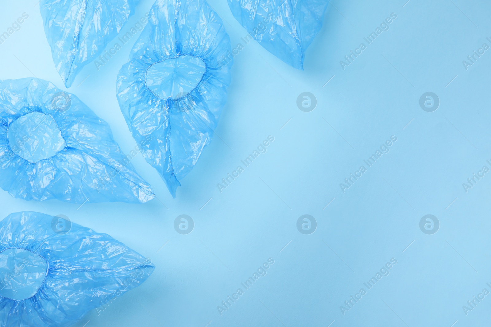 Photo of Medical shoe covers on light blue background, flat lay. Space for text