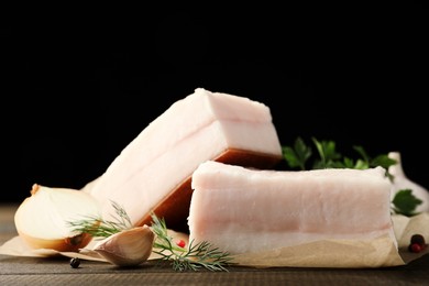Photo of Tasty salt pork with herbs, onion and garlic on wooden table, closeup