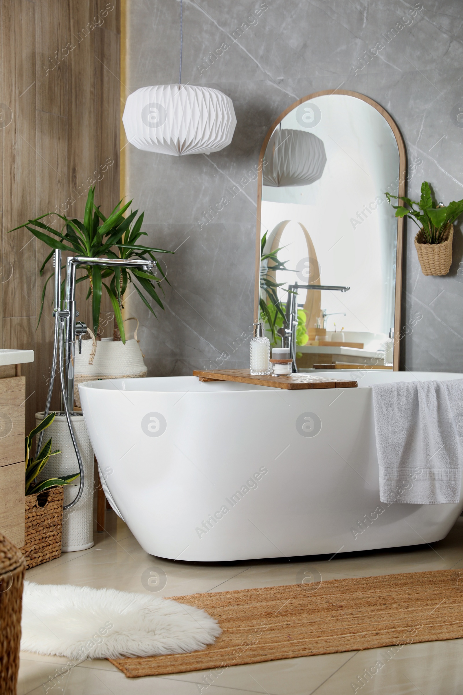 Photo of Modern white tub and beautiful green houseplants in bathroom. Interior design