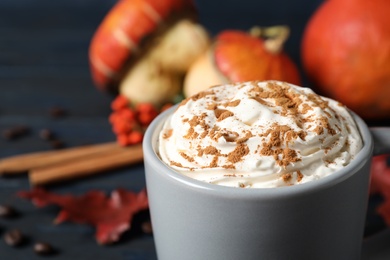 Photo of Cup with tasty pumpkin spice latte on blue wooden table, closeup