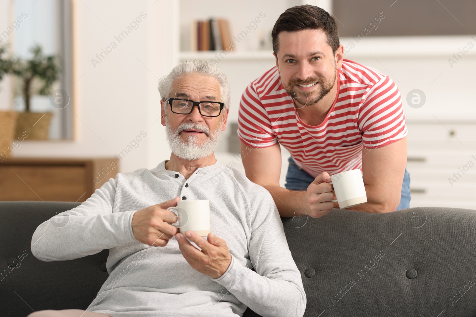 Photo of Happy son and his dad with cups at home