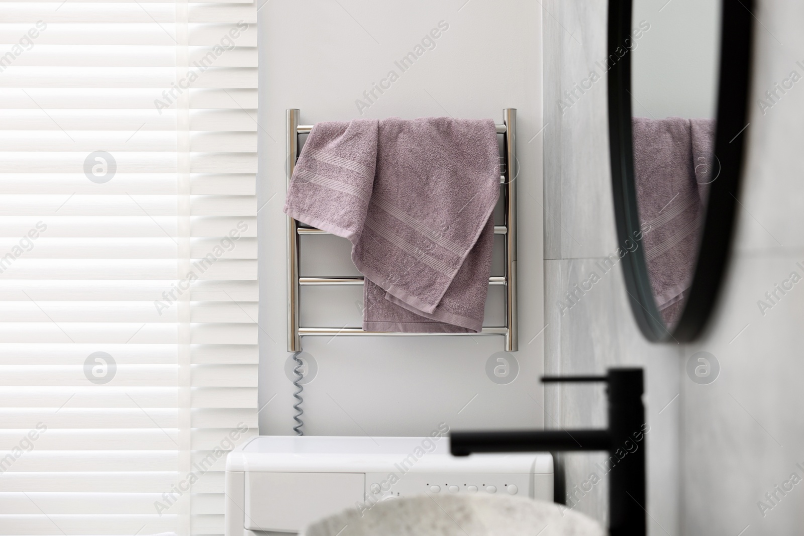 Photo of Clean terry towel on heated rail in bathroom