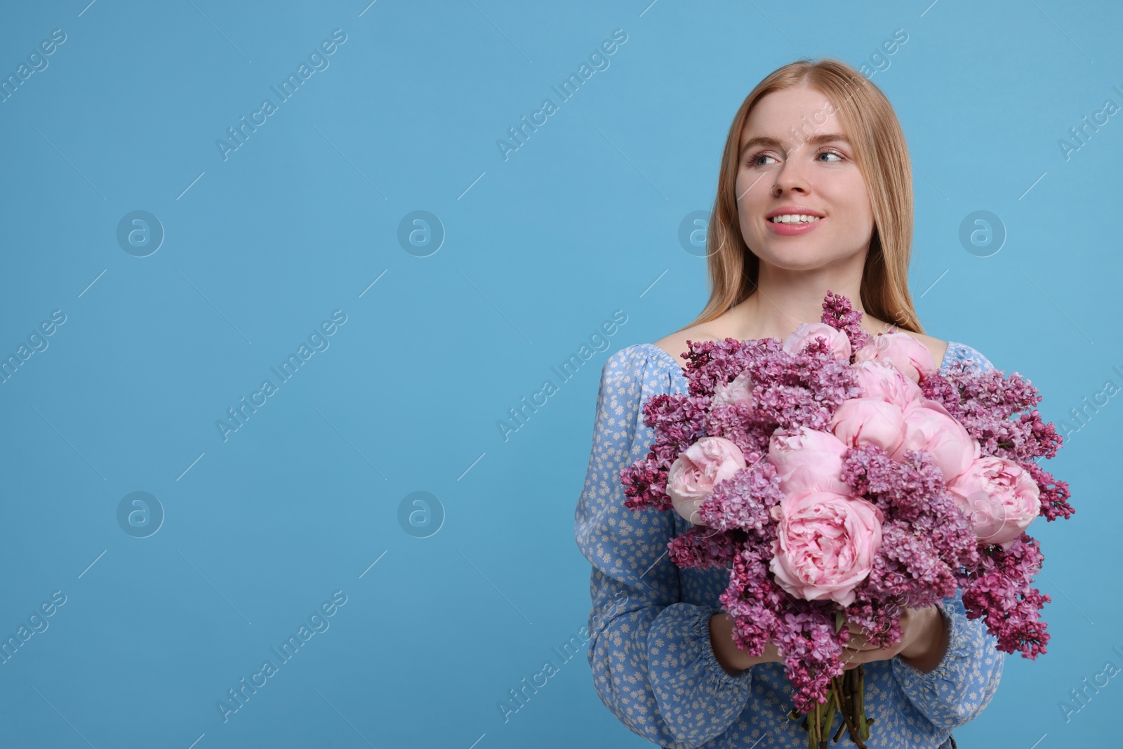 Photo of Beautiful woman with bouquet of spring flowers on light blue background, space for text