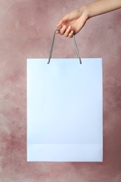 Photo of Woman holding paper shopping bag on color background