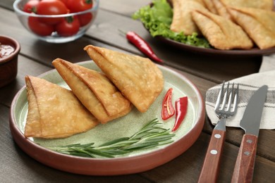 Photo of Fresh delicious crispy samosas served on wooden table