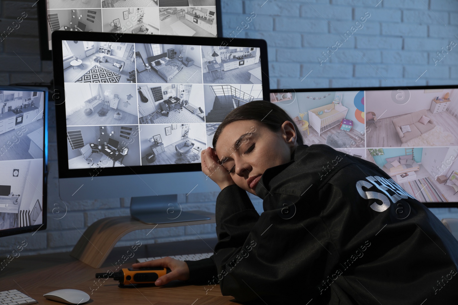 Photo of Female security guard sleeping near monitors at workplace