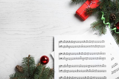 Flat lay composition with Christmas music sheets on white wooden background, space for text