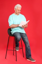 Photo of Senior man reading book on color background