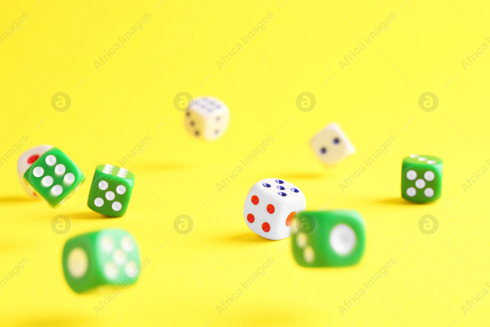 Photo of Many color game dices falling on yellow background