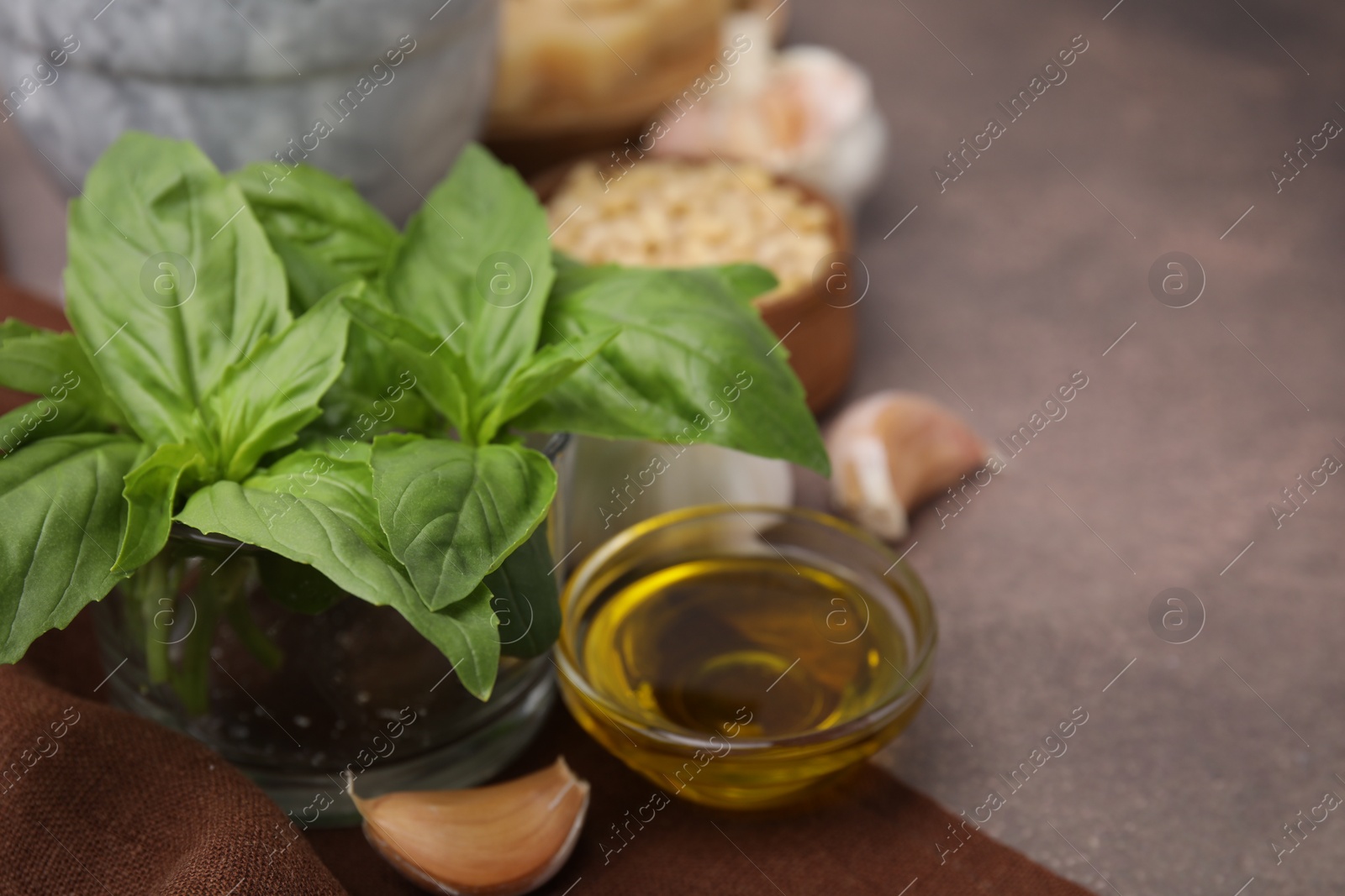 Photo of Different ingredients for cooking tasty pesto sauce on brown textured table, closeup. Space for text