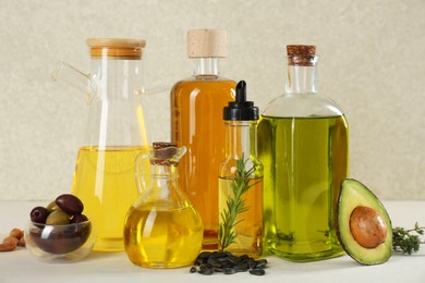Photo of Vegetable fats. Different cooking oils in glass bottles and ingredients on white table