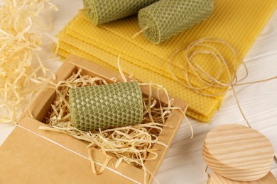 Stylish elegant beeswax candles, wax sheets and twine on white wooden table