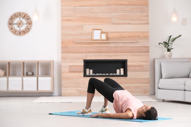 Photo of Young woman in fitness clothes doing exercise at home