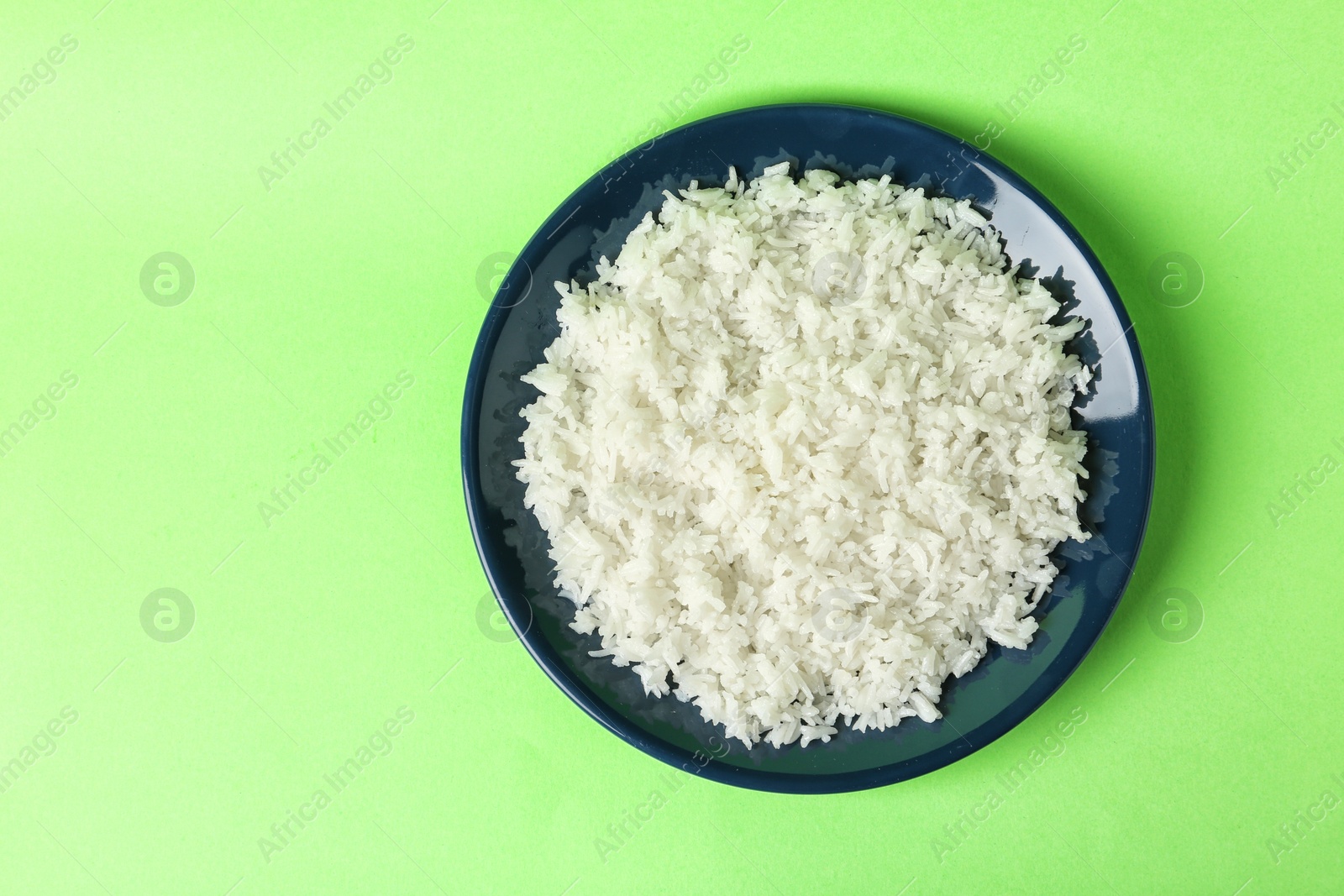 Photo of Plate of boiled rice on color background, top view with space for text