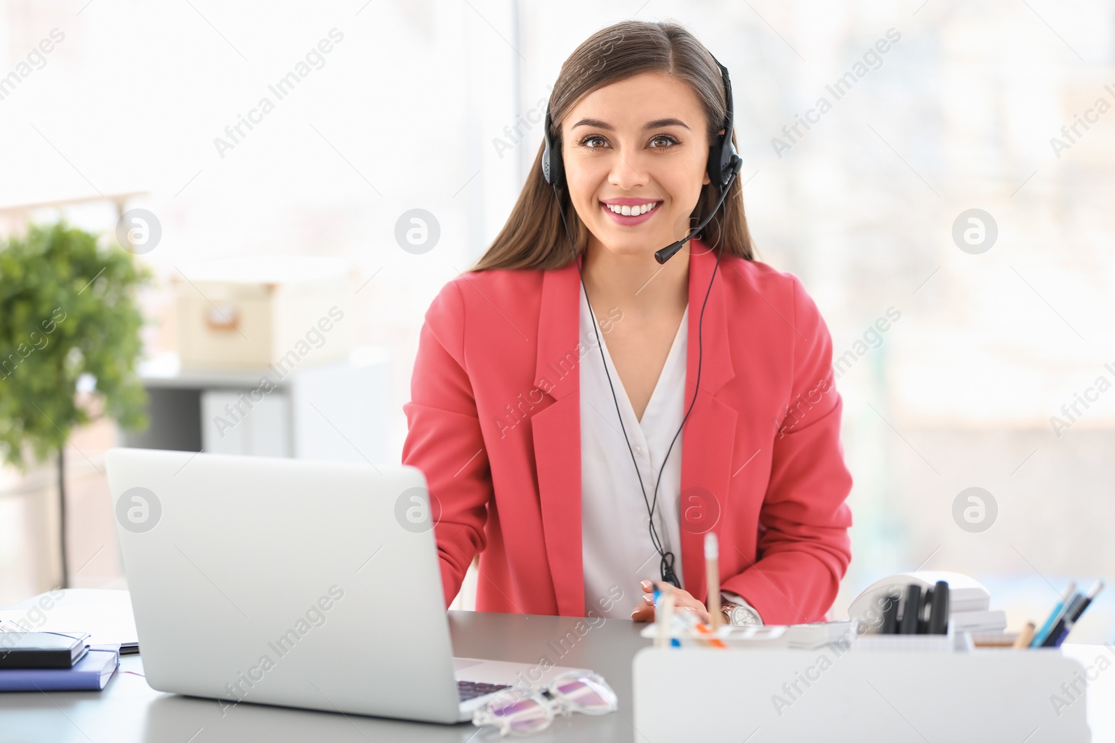 Photo of Young woman talking on phone through headset at workplace