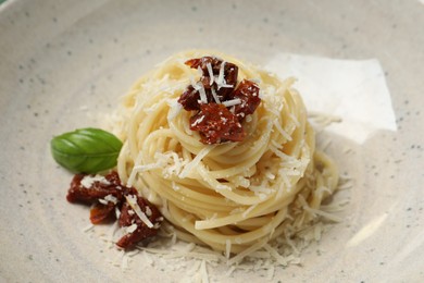 Photo of Tasty spaghetti with sun-dried tomatoes and cheese on plate, closeup. Exquisite presentation of pasta dish