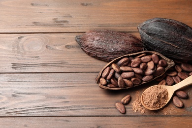Photo of Flat lay composition with cocoa pods, beans and powder on wooden table, space for text