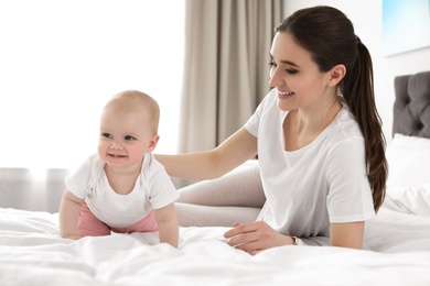 Photo of Adorable little baby crawling near mother on bed indoors