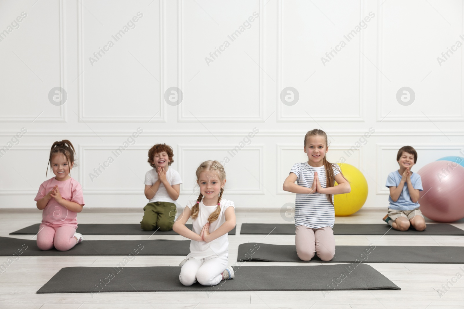 Photo of Group of children doing gymnastic exercises on mats indoors