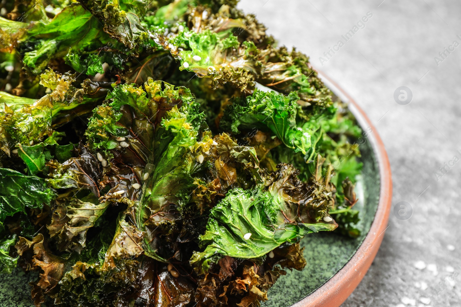 Photo of Tasty baked kale chips on grey table, closeup