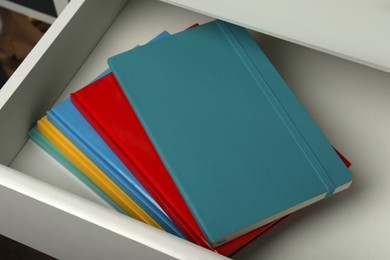 Photo of Stack of colorful planners in open drawer, closeup