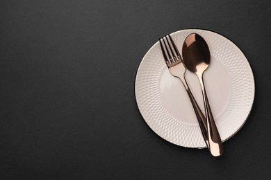 Photo of Clean plate and cutlery on black table, top view. Space for text