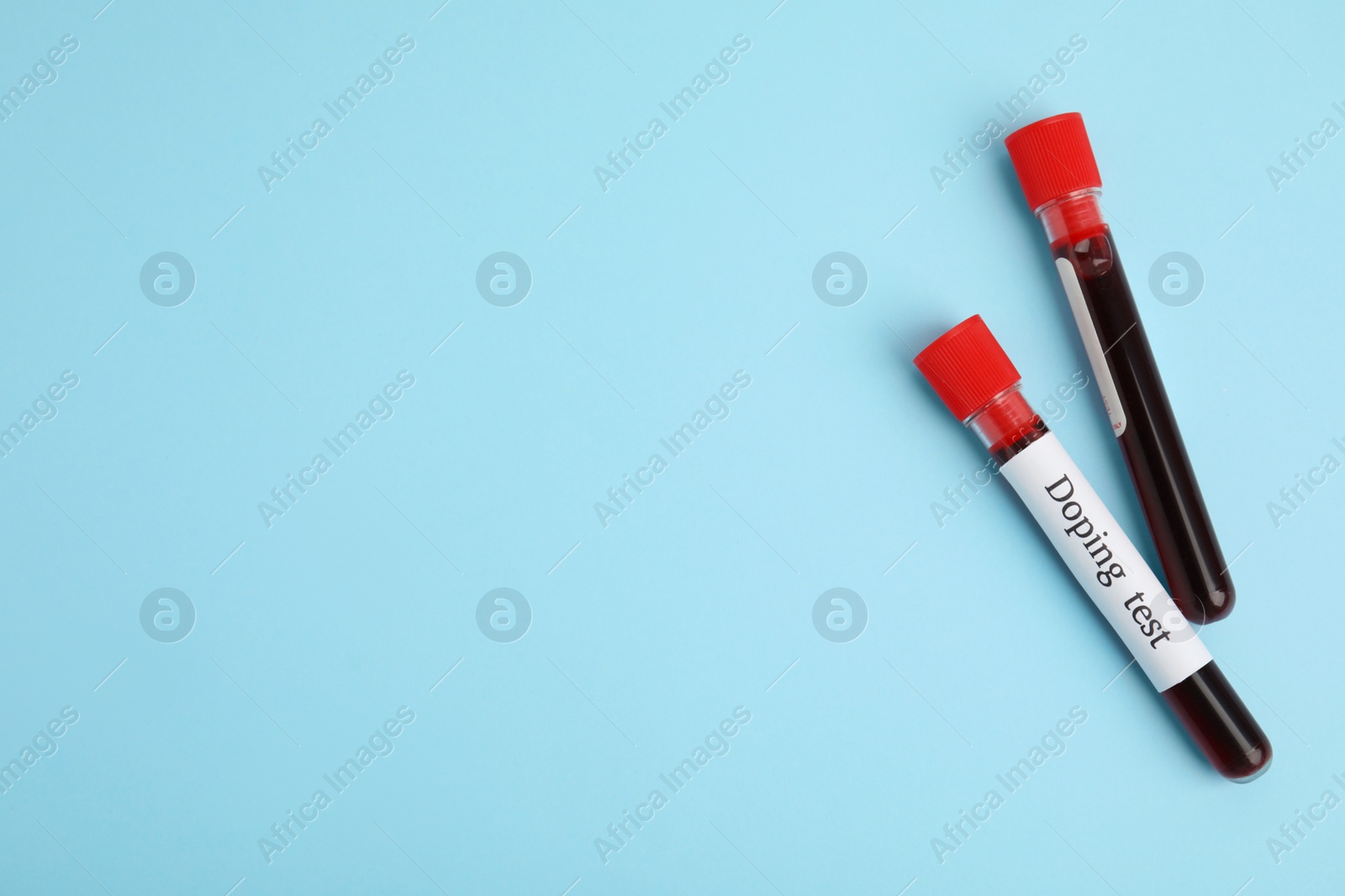 Photo of Test tubes with blood samples on light blue background, flat lay and space for text. Doping control